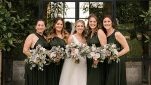 Bride and Bridesmaids in green dresses holding flowers at wedding venue in Cotswolds