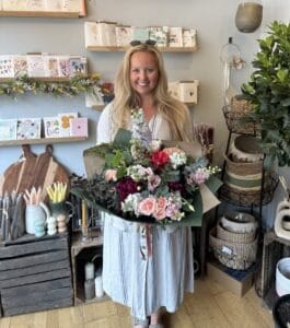 Customer who attended a bouquet workshop proudly displaying her hand tied bouquet in the flower shop