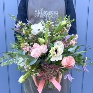 Vase full of flowers in soft pink, ivory and green tones