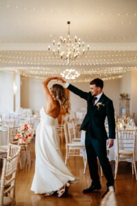 Bride and groom dancing at their wedding reception carrying florals