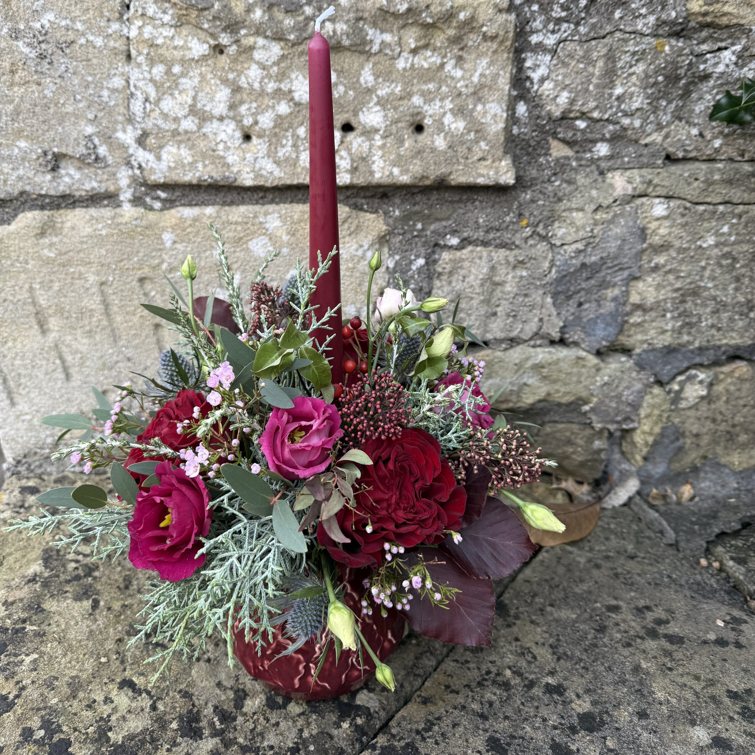 Florals in a burgundy ceramic pot with candle for christmas